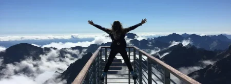 Woman at top of mountain celebrating after overcoming life's hurdles